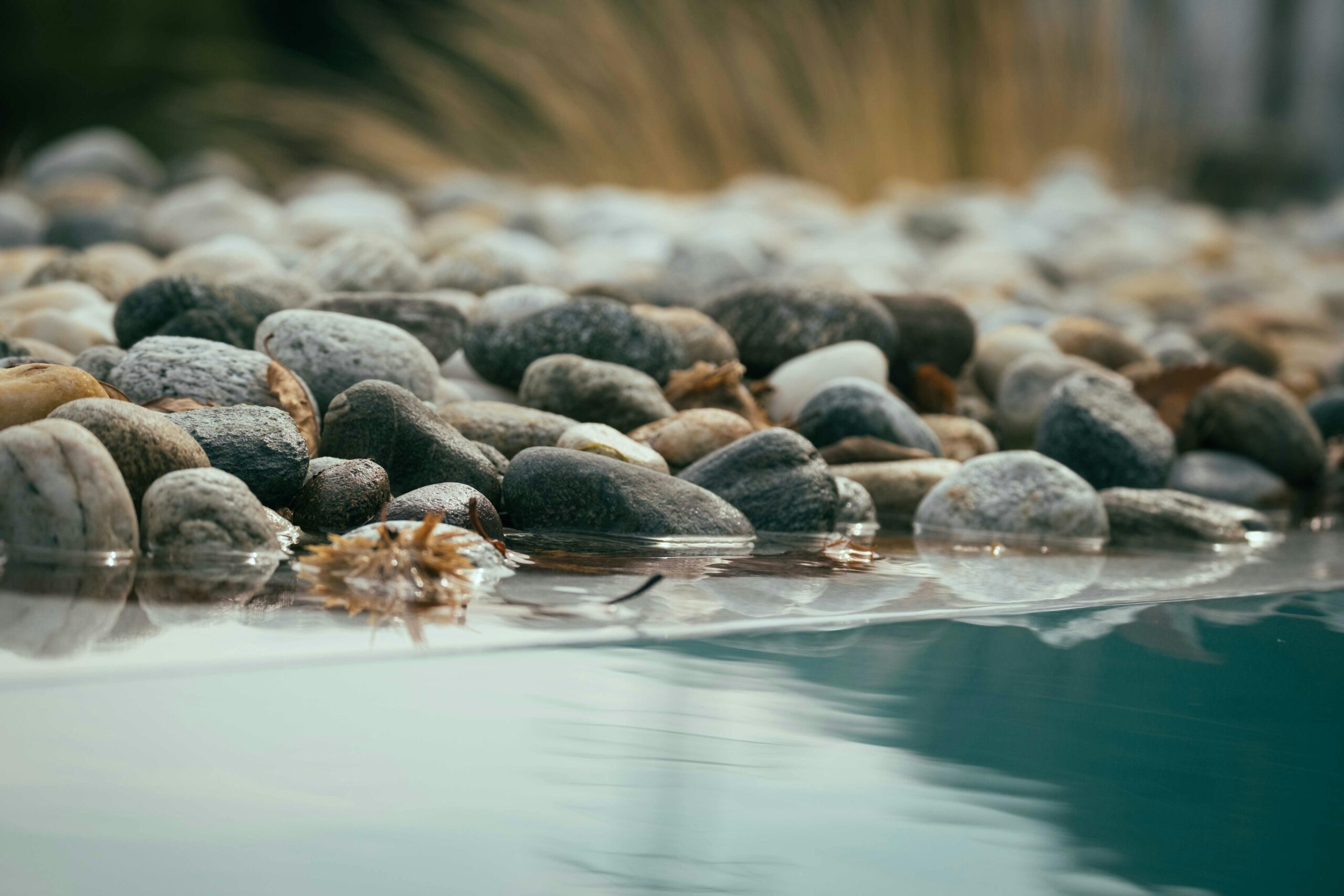 A tranquil lakeside scene featuring smooth pebbles along the shore, reflecting peaceful nature.
